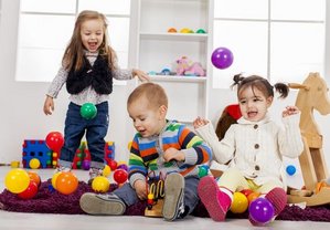 Drei Kinder spielen gemeinsam mit Bällen