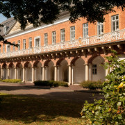 Zweigeschossiger Marstall von Aurich, erbaut im Barockstil. Im Untergeschoss Arkadengang mit Tudorbögen. Im Obergeschoss Balkon mit schmiedeeisernem Geländer und Giebeldreieck. 