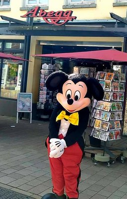 Eine Person als Micky Maus kostümiert posiert in der Auricher Innenstadt vor einem Geschäft 