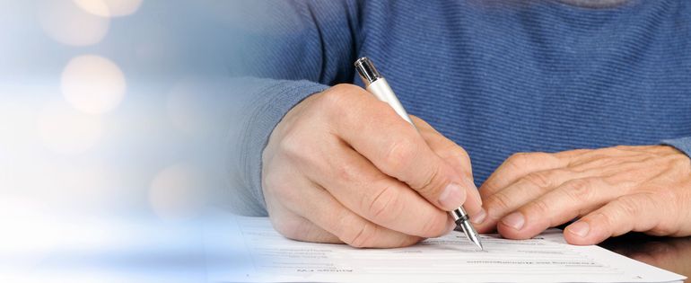 Eine Person füllt mit einem Stift ein Formular aus 