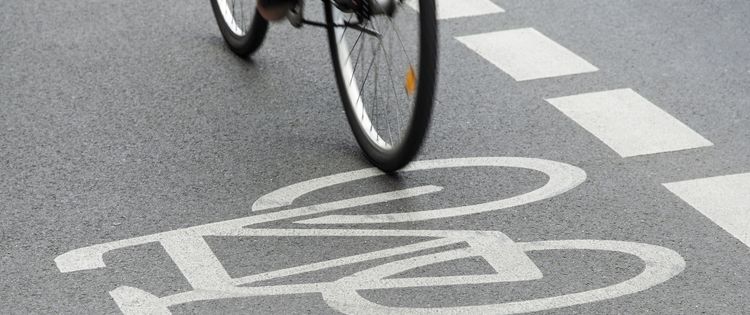 Eine Person auf einem Fahrrad befährt einen Fahrradweg 