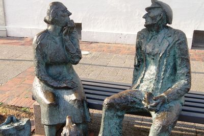 Moorbauernpaar sitzt auf einer Bank vor dem Historischen Museum, von Friedrich Büschelberger