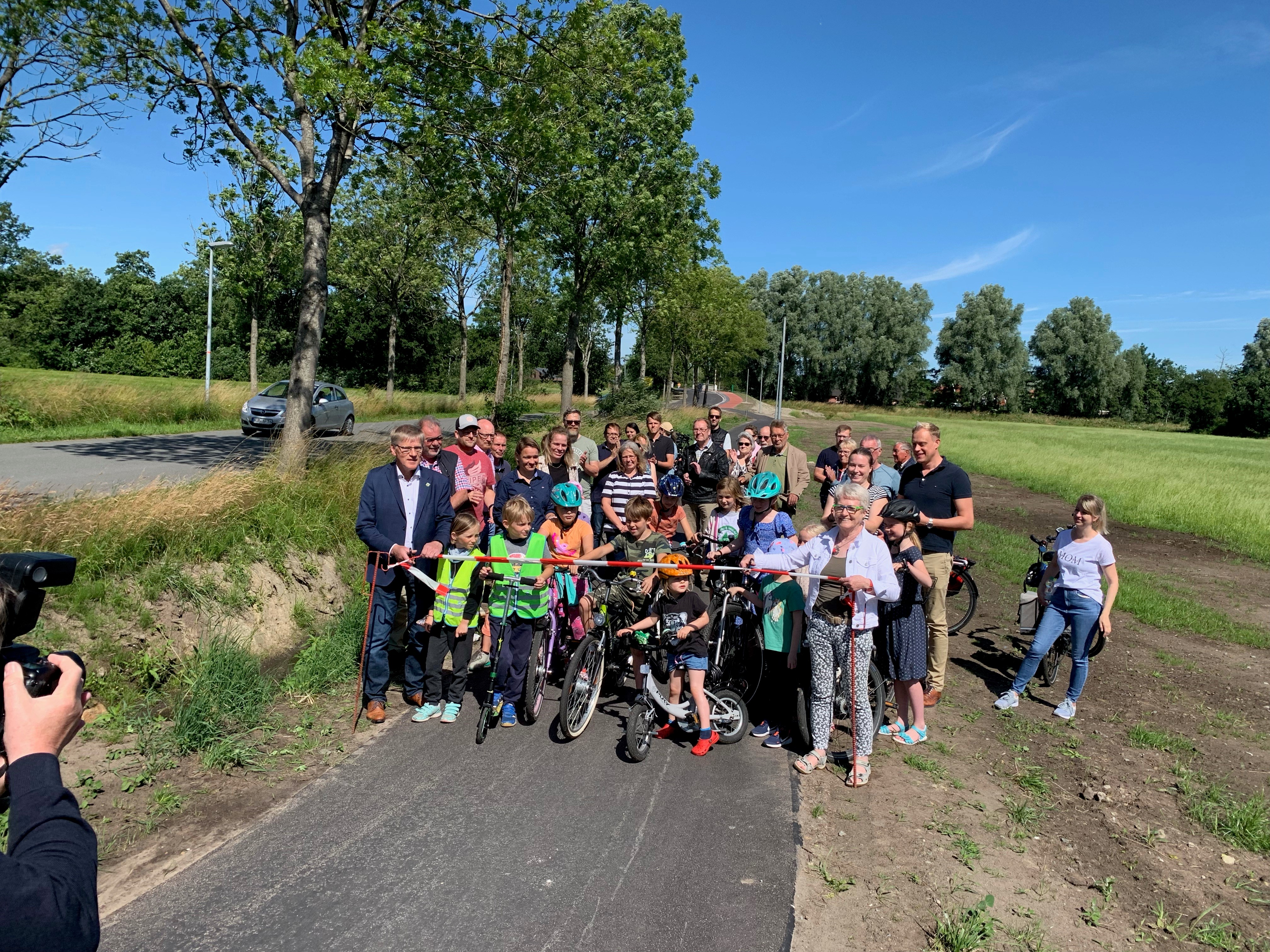 Eine Gruppe mit Kindern und Erwachsenen eröffnet einen Radweg 