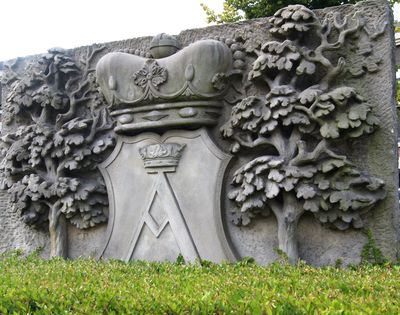 Auricher Wappenstein vor dem Rathaus. Das Wappen der Stadt zeigt zwischen zwei Bäumen einen gekrönten Schild. Darin ein gotisches großes A. 