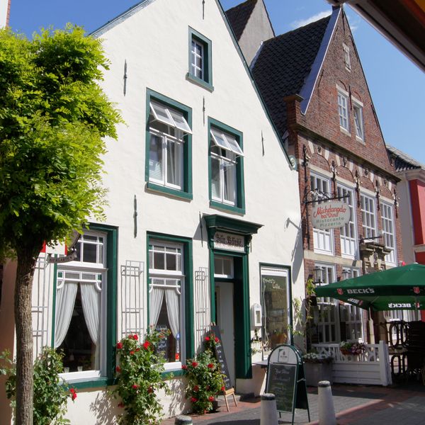 Links das weiß verputzte Haus mit dem Namen Zur Börse. Rechts daneben ein Haus mit roten Klinkern.   