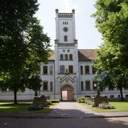 Das Schloss im englischen Tudorstil des Historismus. Weisser Anstrich. Turm im Südflügel. 