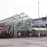 Der gepflasterte Marktplatz. In der Mitte des Marktplatzes steht die Markthalle mit einem gläsernen Eingangsbereich. 