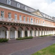 Zweigeschossiger Marstall von Aurich, erbaut im Barockstil. Im Untergeschoss Arkadengang mit Tudorbögen. Im Obergeschoss Balkon mit schmiedeeisernem Geländer und Giebeldreieck. 
